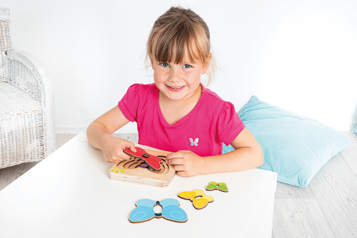 Ein Mädchen spielt das Lagen-Puzzle "Kleiner Schmetterling"
